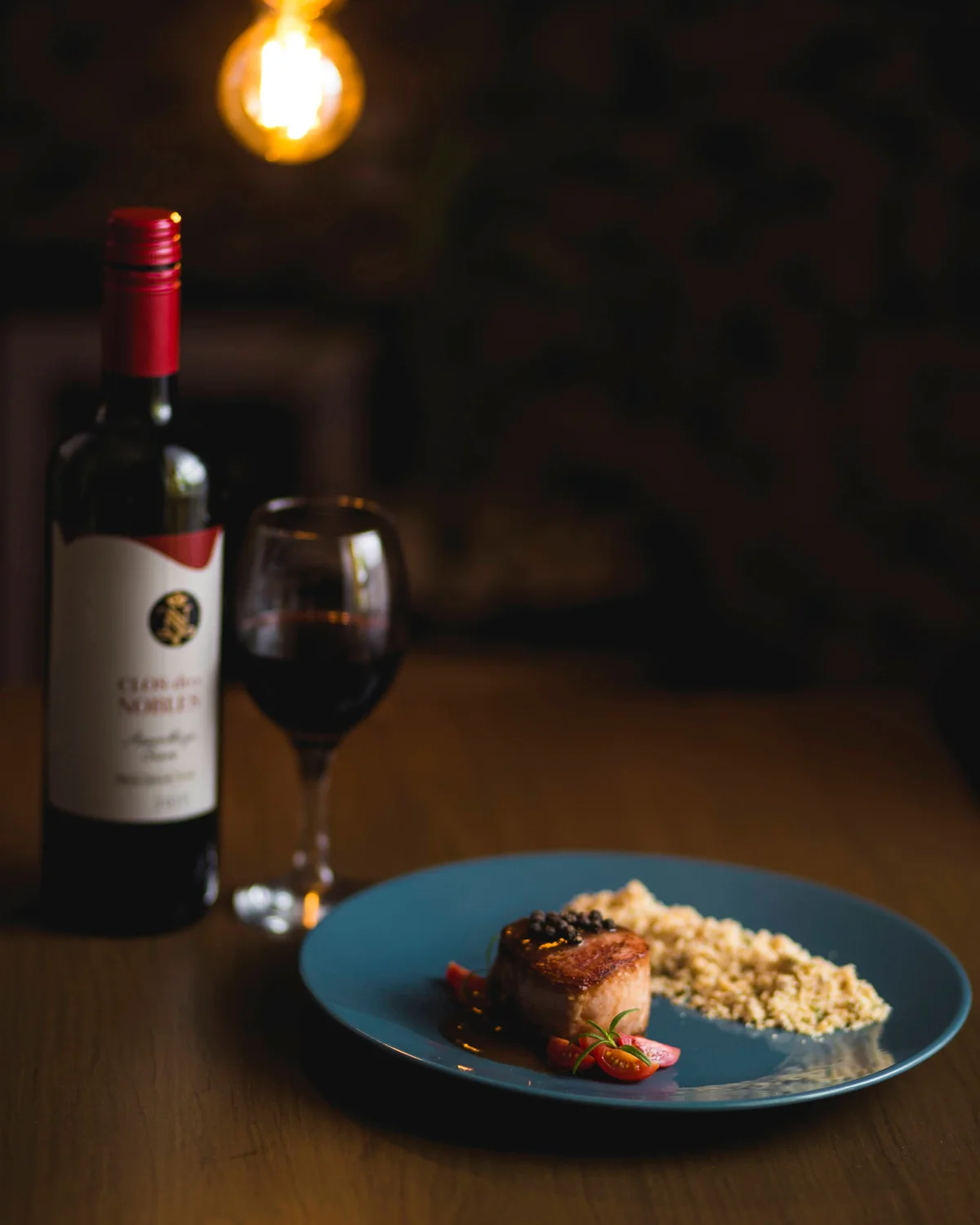 Prato servido ao lado de uma garrafa e uma taça de vinho tinto